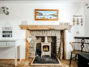 A cozy room with a stone fireplace, a white wall, and a wooden mantel. - 5 bedroom accommodation in Aberaeron (Aberaeron)