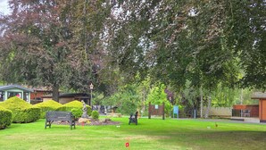 A park with benches, a statue, and a small building.