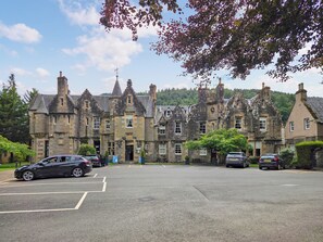 A historic stone building with multiple chimneys and a clock tower. - 2 bedroom accommodation in Birnam (Birnam)