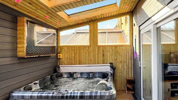 A hot tub in a wooden cabin with a skylight and large windows. - Spacious family home with games, a private hot tub and coastal adventures. (Whitby)