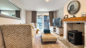 A living room with a sofa, ottoman, TV, fireplace, and a large mirror. - Spacious family home with games, a private hot tub and coastal adventures. (Whitby)