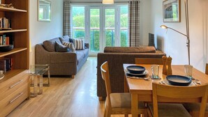 A modern living room with a sofa, dining table, and bookshelf. - 1 bedroom accommodation in Newquay (Newquay)
