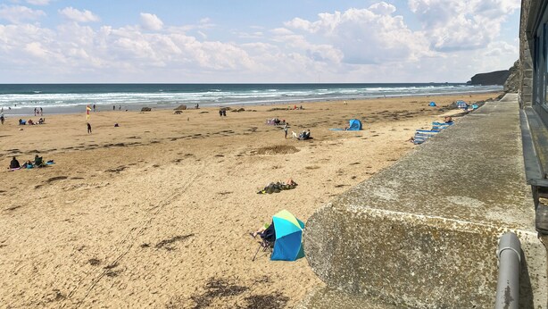 A beach with people, tents, and a flag. - 1 bedroom accommodation in Newquay (Newquay)
