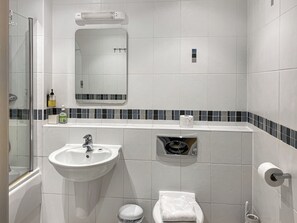 Et badeværelse med vask, spejl, toilet og bruser.