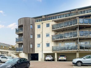 A multi-story building with balconies, a parking area, and a clear sky. - 1 bedroom accommodation in Newquay (Newquay)