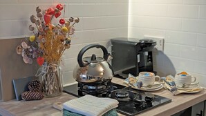 A kitchen counter with a kettle, a vase with dried flowers, a coffee maker, and a tea set. - Raygill Shepherds Hut (Dishforth, near Thirsk)