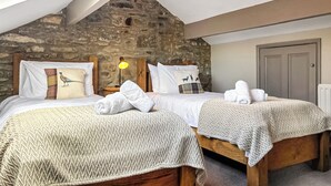Een slaapkamer met twee bedden, een stenen muur, een houten plafond en een dakraam.