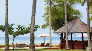 A gazebo with a wooden roof and a view of the ocean.
