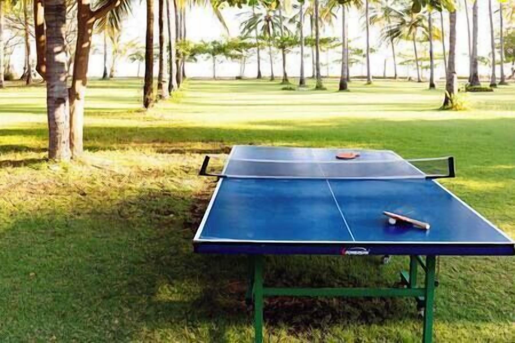 A ping pong table in a grassy area with trees in the background.