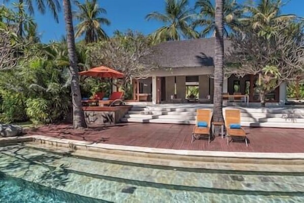 A resort with a pool, lounge chairs, and palm trees. - The Anandita by Elite Havens (Lombok Utara)