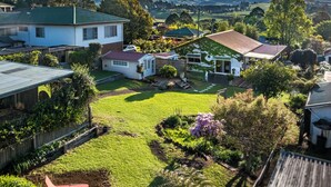 A residential area with houses, a well-maintained lawn, and a clear view of the surrounding landscape. - Charming 1940's two bedroom cottage, established gardens, large verandah and BBQ (Dorrigo)
