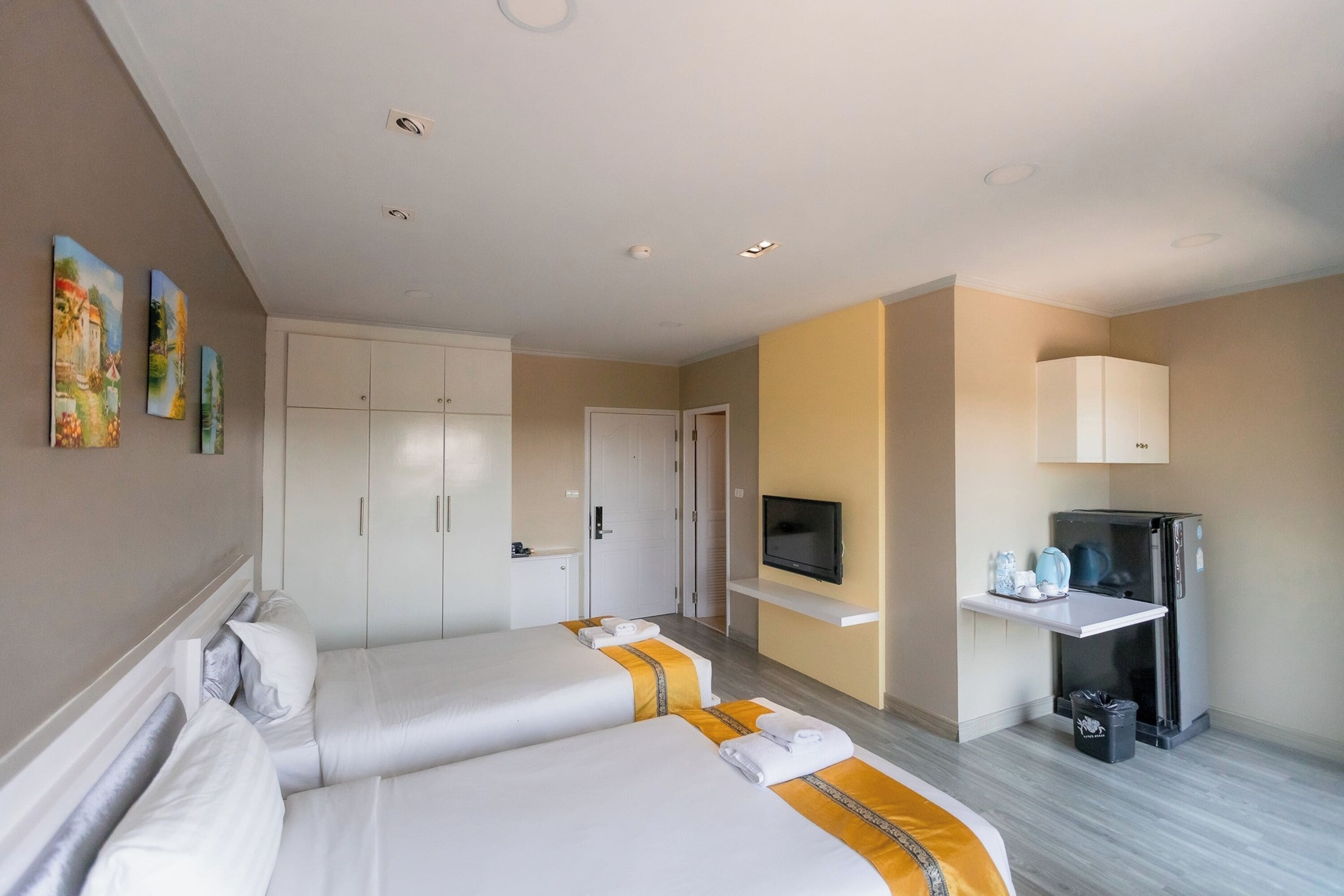 A hotel room with two beds, a TV, a refrigerator, and a minibar.