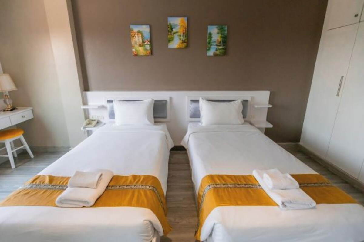 Une chambre d’hôtel avec deux lits, un bureau et une chaise.