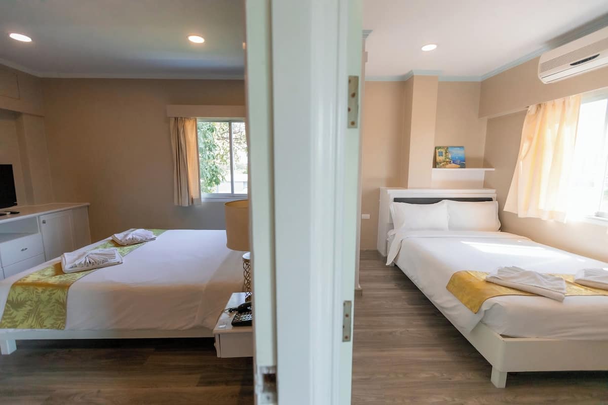 Ein Hotelzimmer mit zwei Betten, einem Fernseher, einem Schreibtisch und einem Fenster mit Vorhängen.