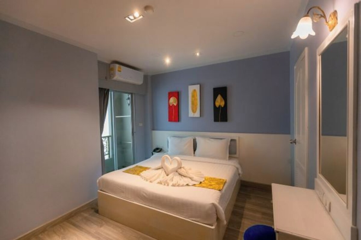 Une chambre d’hôtel avec un lit, une table de chevet et un miroir.