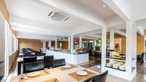 Un amplio comedor de hotel con varias mesas, una isla central y un sistema de buffet.