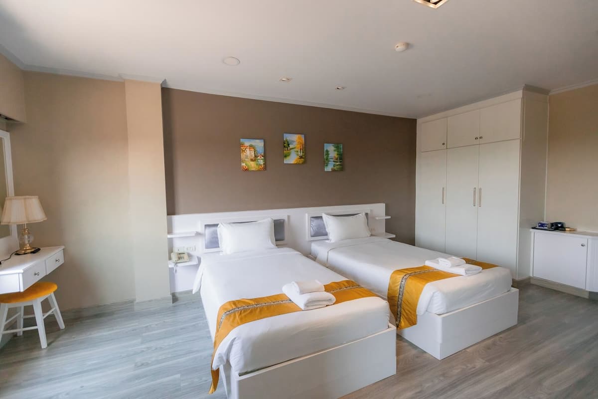 Ein Hotelzimmer mit zwei Betten, einem Schreibtisch und einem Kleiderschrank.