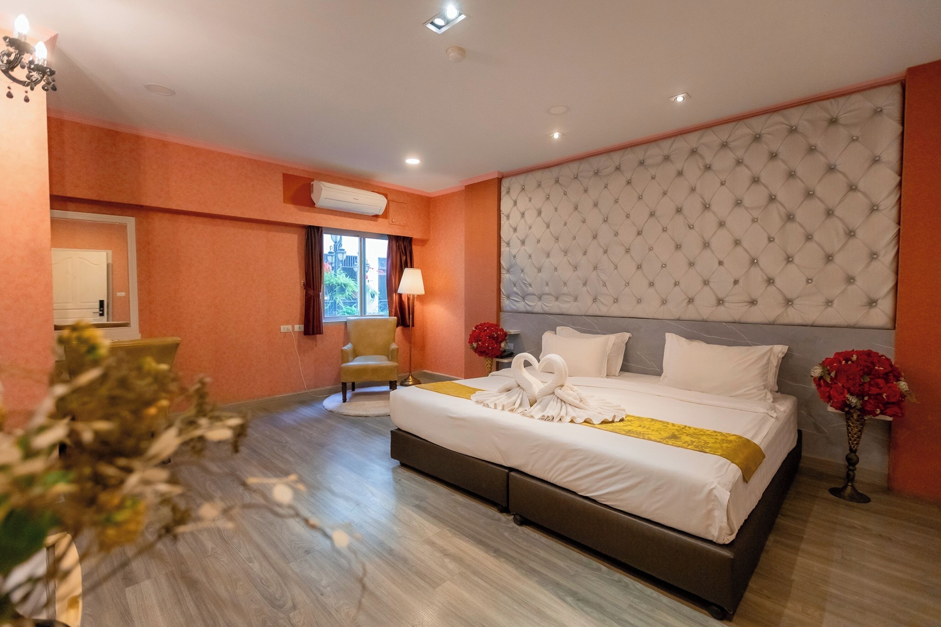 A hotel room with a large bed, a chair, an air conditioning unit, and a view of the outside.