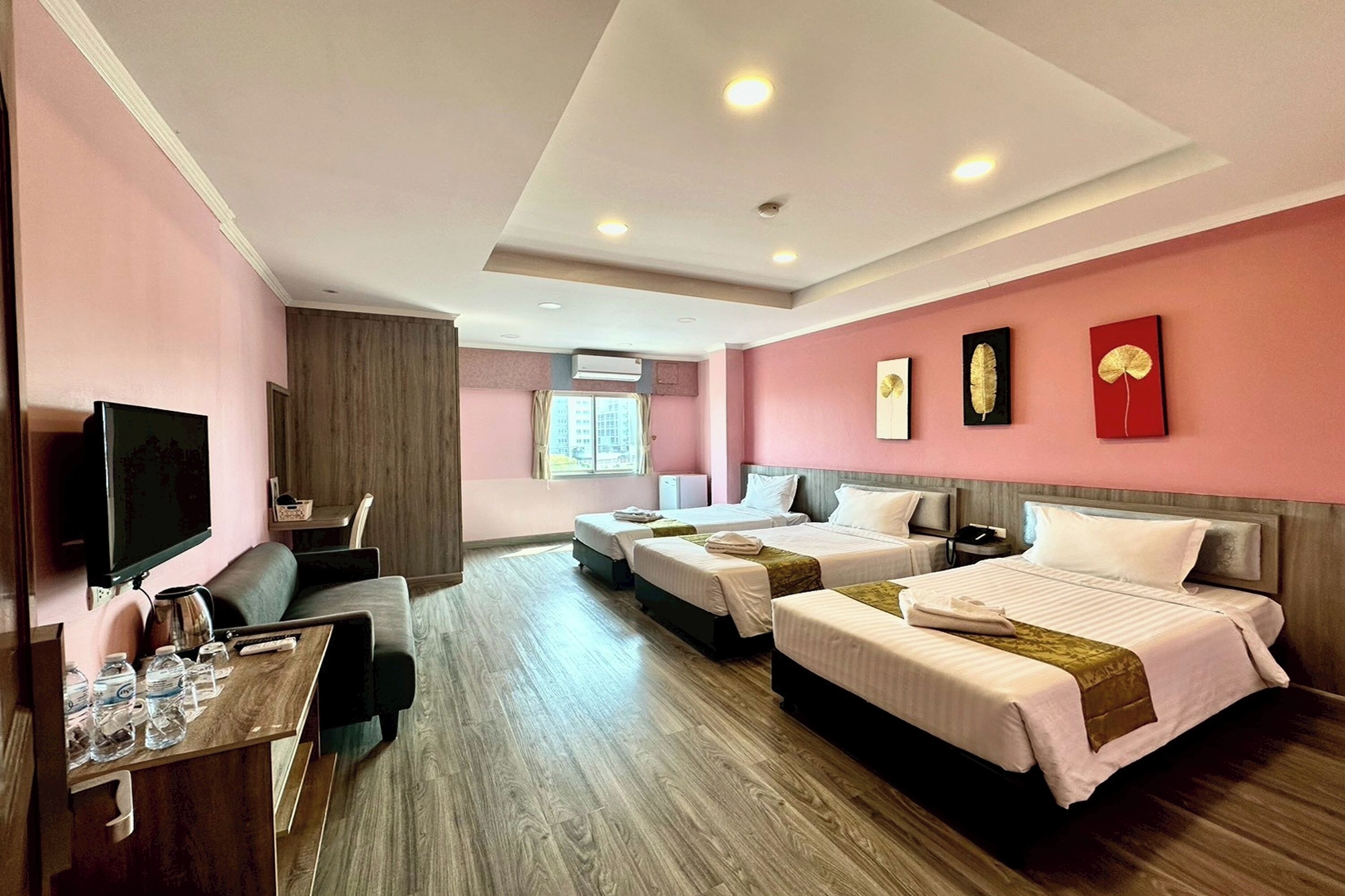 A hotel room with two beds, a TV, a desk with a chair, and a window with curtains.