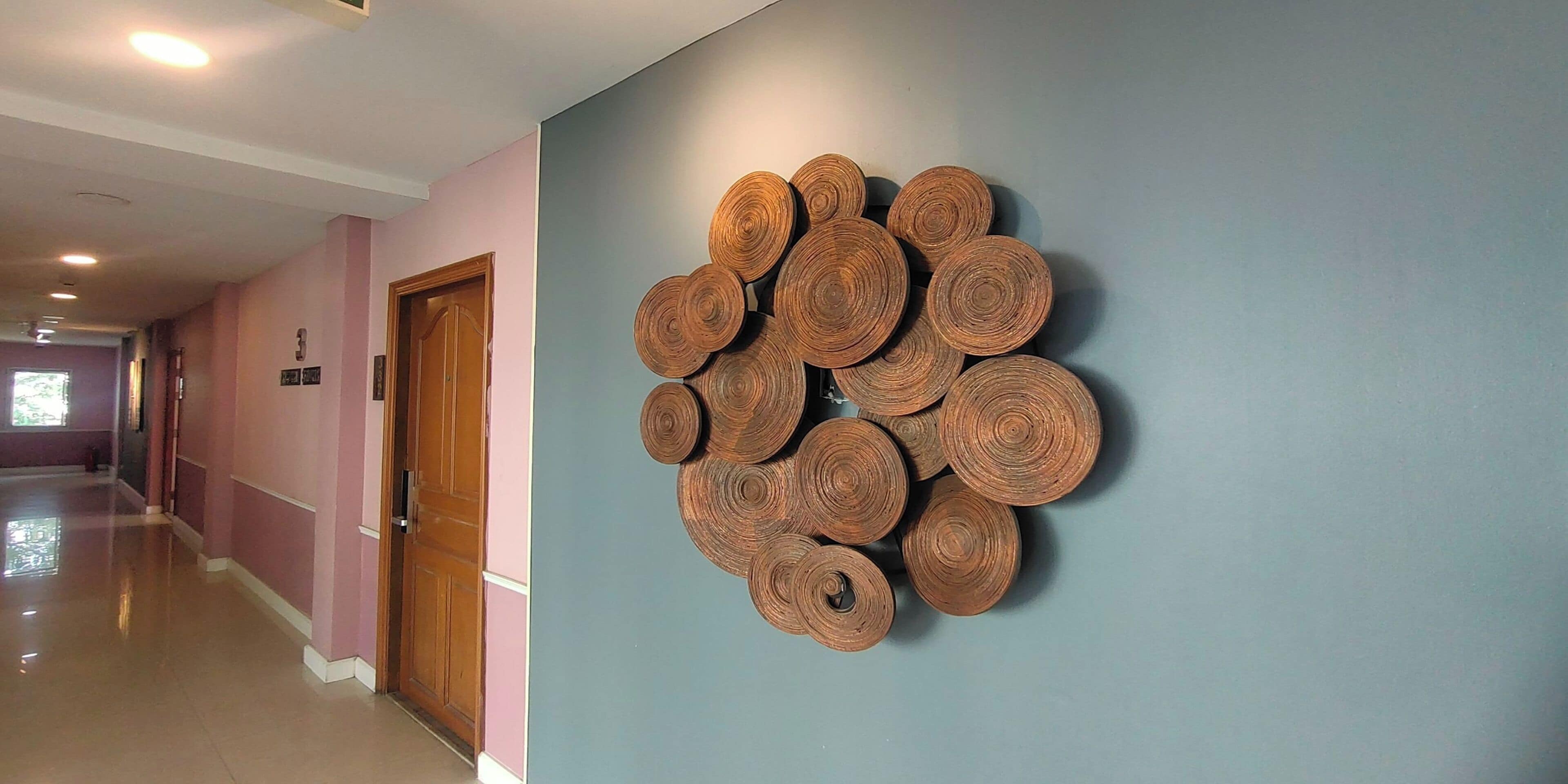 Un pasillo con una puerta de madera y un adorno de madera fijado a la pared.