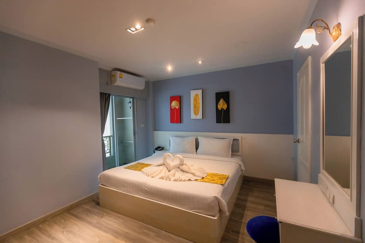 Ein Hotelzimmer mit Bett, Nachttisch und Spiegel.