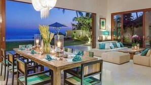 Un comedor con vistas al océano, un conjunto de sofás y un ventilador de techo.
