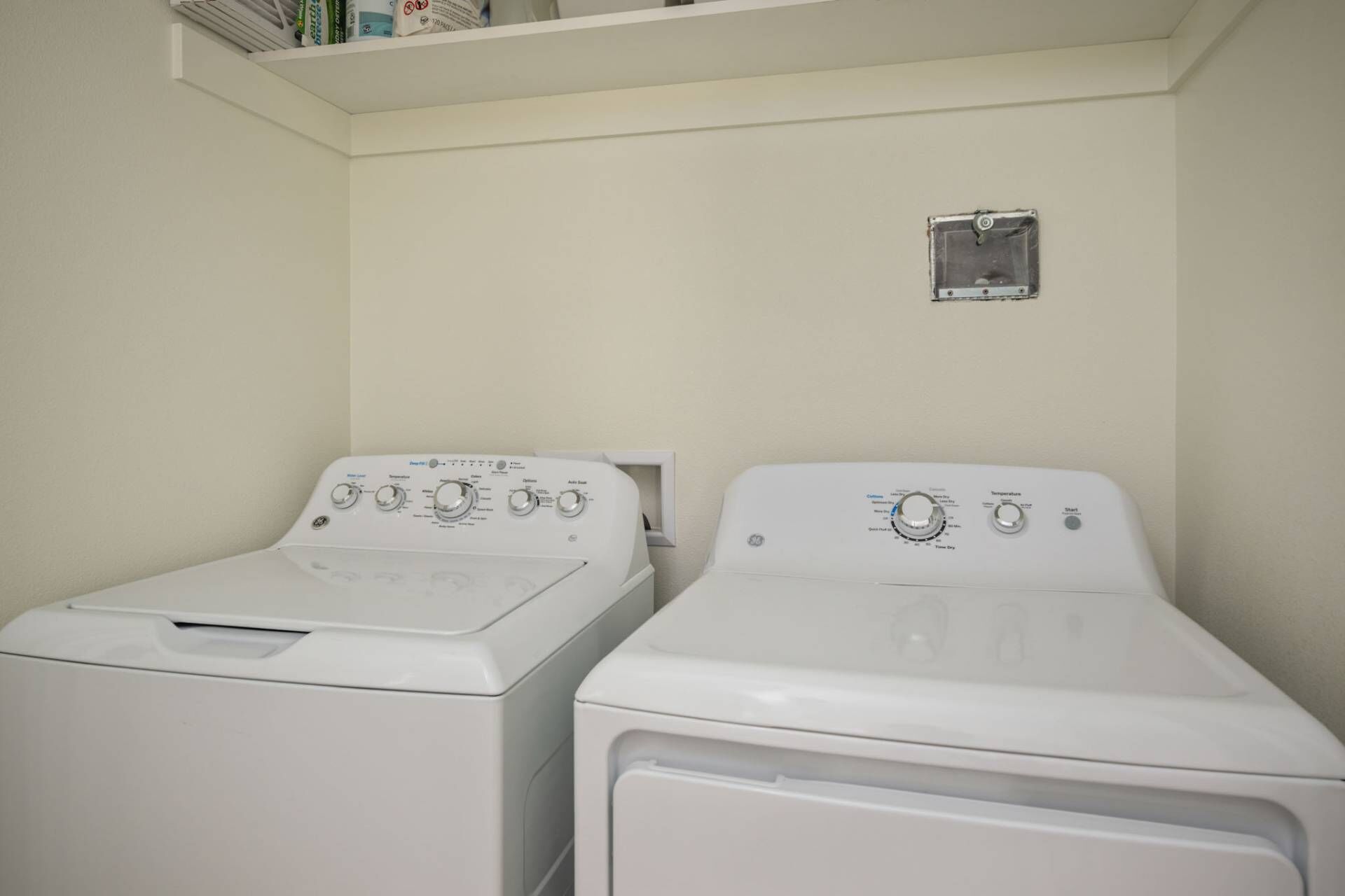 Two front-loading washing machines in a laundry room with a small window above them.