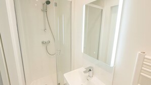 A modern bathroom with a glass-enclosed shower, a white sink, and a mirror above it. - Studio Paris 15ème: Proche Métro Parfait pour 2 (Paris)