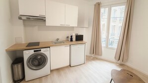 A compact kitchen with a washing machine, a small fridge, and a sink. - Studio Paris 15ème: Proche Métro Parfait pour 2 (Paris)