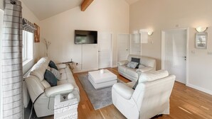 A modern living room with a sofa set, a coffee table, and a flat-screen TV mounted on the wall. - 3 bedroom accommodation in Brigg (Brigg)