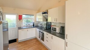 A modern kitchen with white cabinets, a stainless steel range hood, a microwave, and a sink. - 3 bedroom accommodation in Brigg (Brigg)