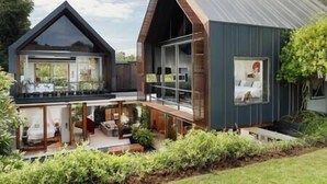 Une maison moderne dotée d’une grande baie vitrée, d’un balcon et d’une terrasse en bois.