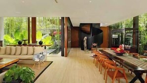 Un salon moderne avec un canapé, une table à manger et des chaises. Une grande fenêtre offre une vue sur la verdure à l’extérieur.