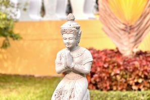 Une statue représentant une figure, placée dans un jardin.