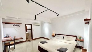 A modern hotel room with a large bed, a desk with a chair, and a small table with a lamp. - SKY Apartments - 50m to National Museum (Phnom Penh)