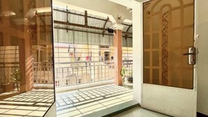 An open door leading to a balcony with a tiled floor and a metal gate. - SKY Apartments - 50m to National Museum (Phnom Penh)