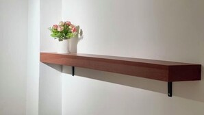 A wooden shelf with a white vase containing pink flowers against a plain wall. - SKY Apartments - 50m to National Museum (Phnom Penh)