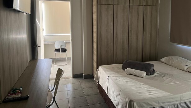 A hotel room with a bed, a desk, a chair, and a TV. - Kris Hotel (Petrolina)