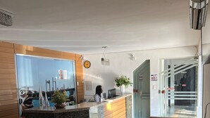 A hotel lobby with a reception desk, a seating area, and a view of the cityscape through large windows. - Kris Hotel (Petrolina)