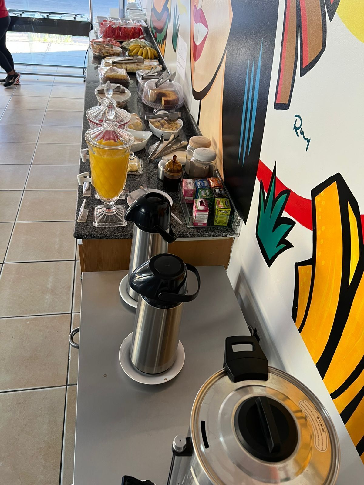 Mostrador de buffet con diversos alimentos y una máquina de café.