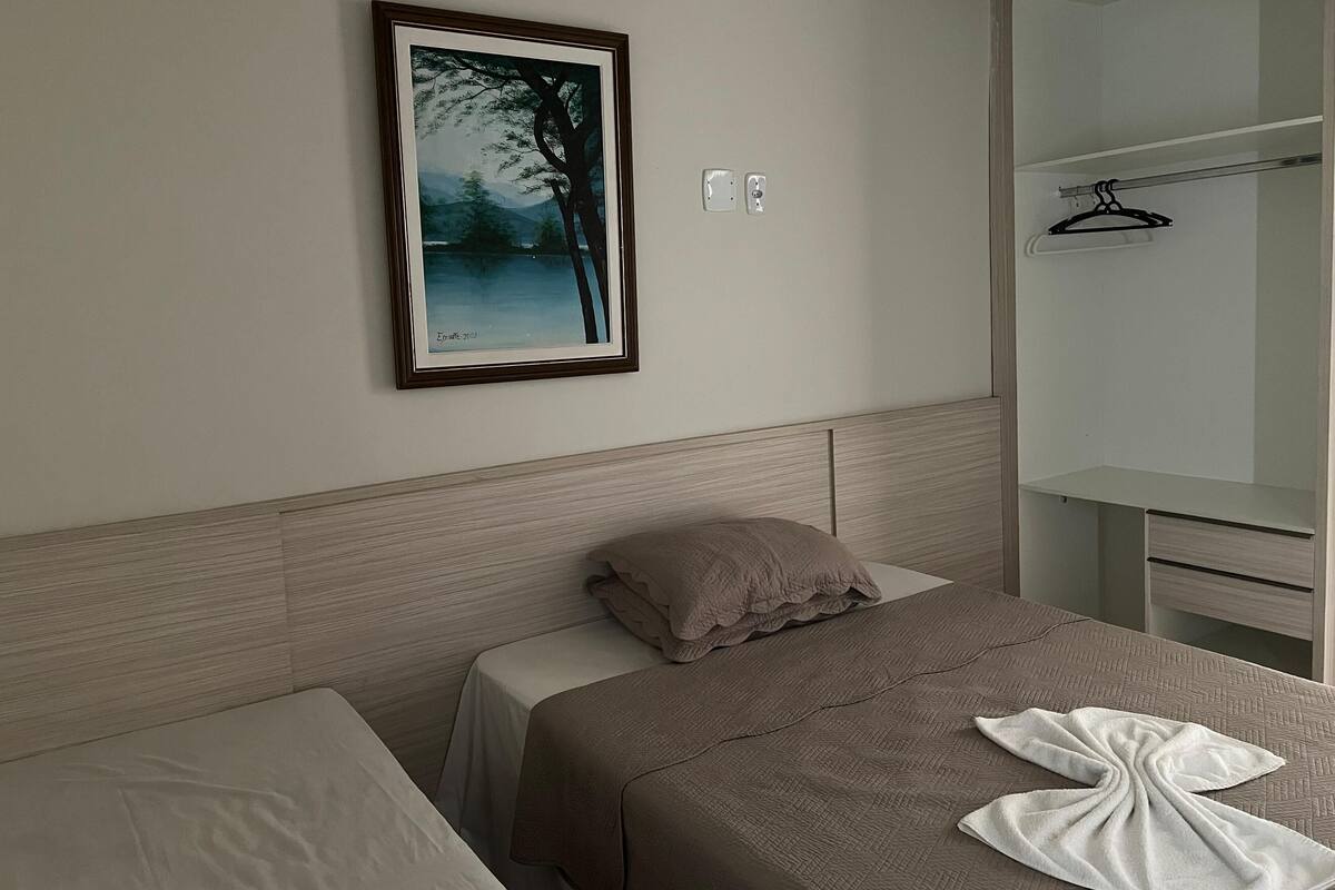 A hotel room with a bed, a bedside table, a wardrobe, and a framed picture on the wall.