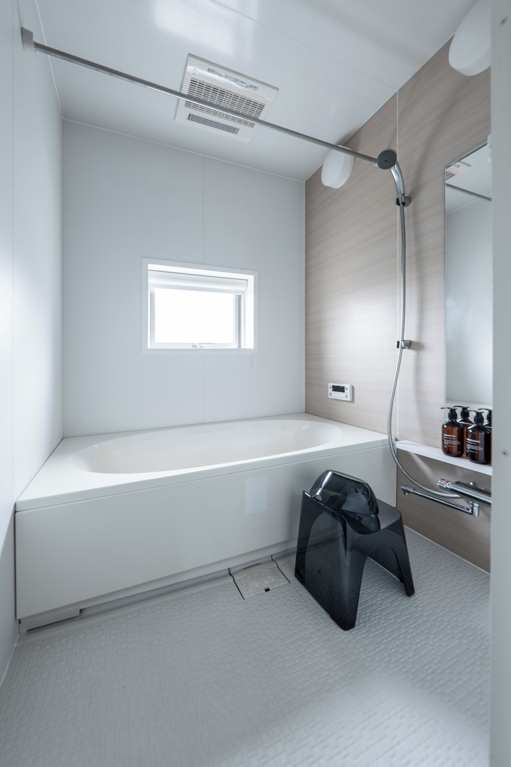 Een moderne badkamer met een witte badkuip, douche, raam en spiegel.