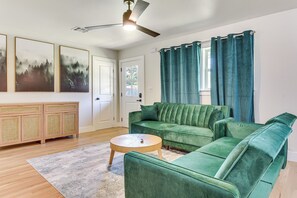 A living room with a green sofa, a wooden cabinet, and a ceiling fan. - 12 Mi to BOK Center: Pet-Friendly Home w/ Yard! (Tulsa)