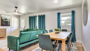 A dining area with a wooden table, green upholstered sofa, and matching chairs. - 12 Mi to BOK Center: Pet-Friendly Home w/ Yard! (Tulsa)