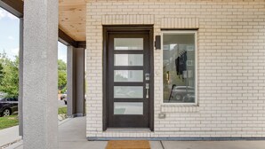 A building with a dark brown door, a small window, and a concrete porch area.