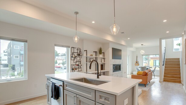 A modern kitchen with a central island, pendant lighting, and a view of the outside.