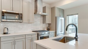 A modern kitchen with white cabinetry, stainless steel appliances, and a large island with a sink.