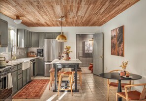 A modern kitchen with a wooden ceiling, stainless steel appliances, and a central island with seating.