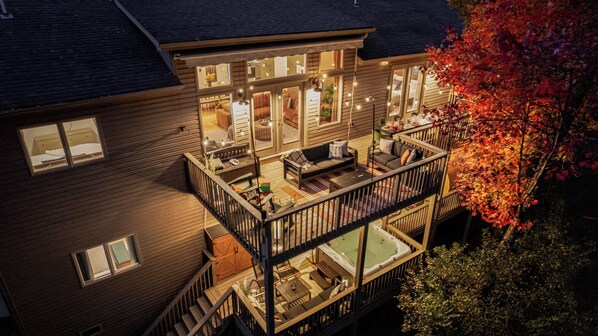 A multi-level house with a balcony, outdoor seating, and a hot tub.