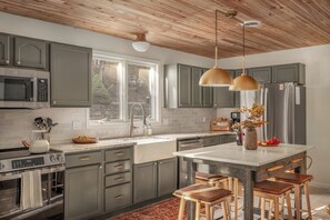 A modern kitchen with grey cabinets, stainless steel appliances, and a large island with stools.